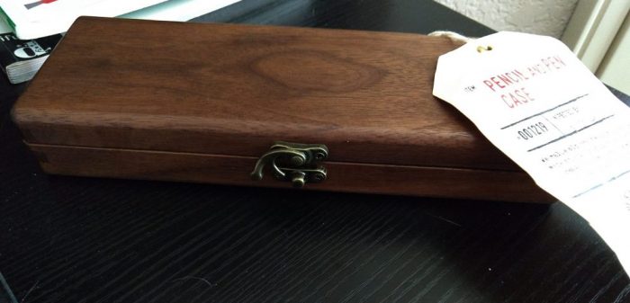 a pencil case made of dark wood, with a brass clasp holding it shut
