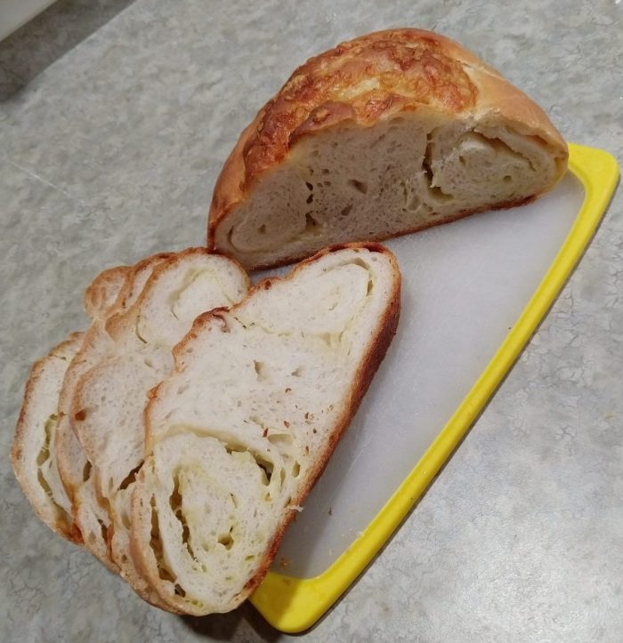 a small loaf of bread, cut in half to reveal swirls of gruyère cheese and with a browned cap of cheese on top