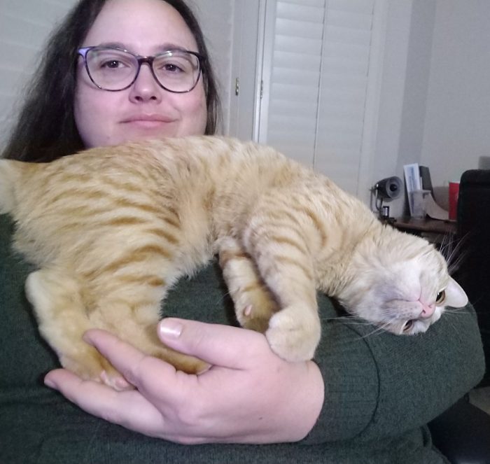 I am holding Fritz the cat in my arm, but he has his back feet in my hand, his head angled down into the bend of my elbow, and his back bumping into my chin because he is a goofball