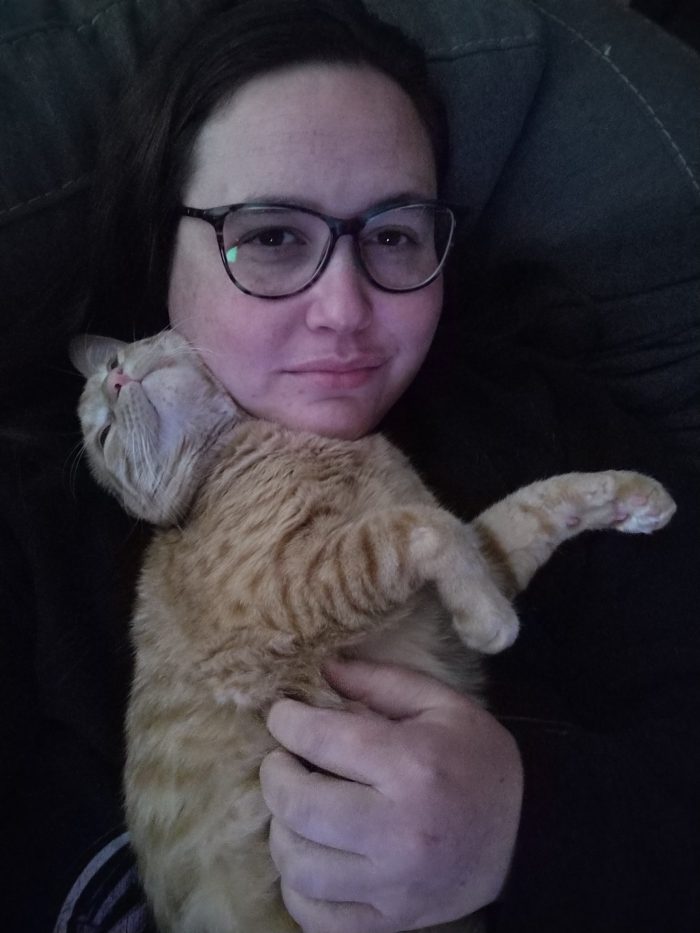 me sitting on the couch with Fritz the cat stretched out on top of me. His head is smooshed up against my cheek and his front paws are in the air