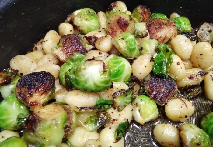 a close-up photo of gnocchi and brussels sprouts in a skillet. the brussels sprouts are charred on the bottom