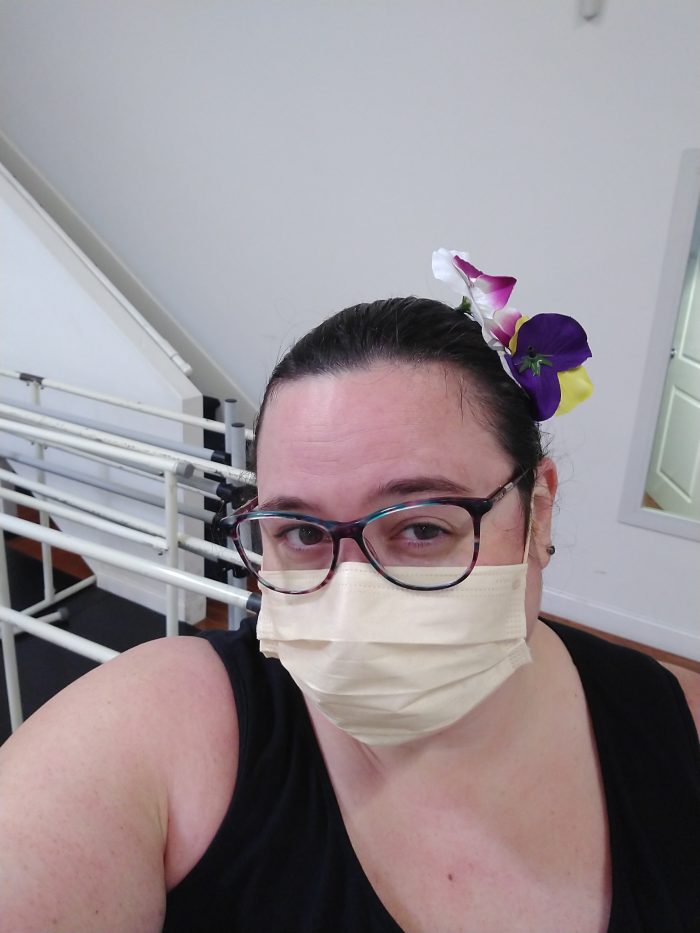 me at the dance studio. I'm wearing a mask and have fake flowers clipped into my hair. There are barres in the background