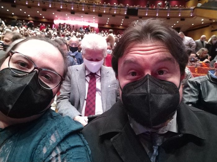 me and Kirk, masked, in a full theater, with audience members milling around and finding their seats behind us