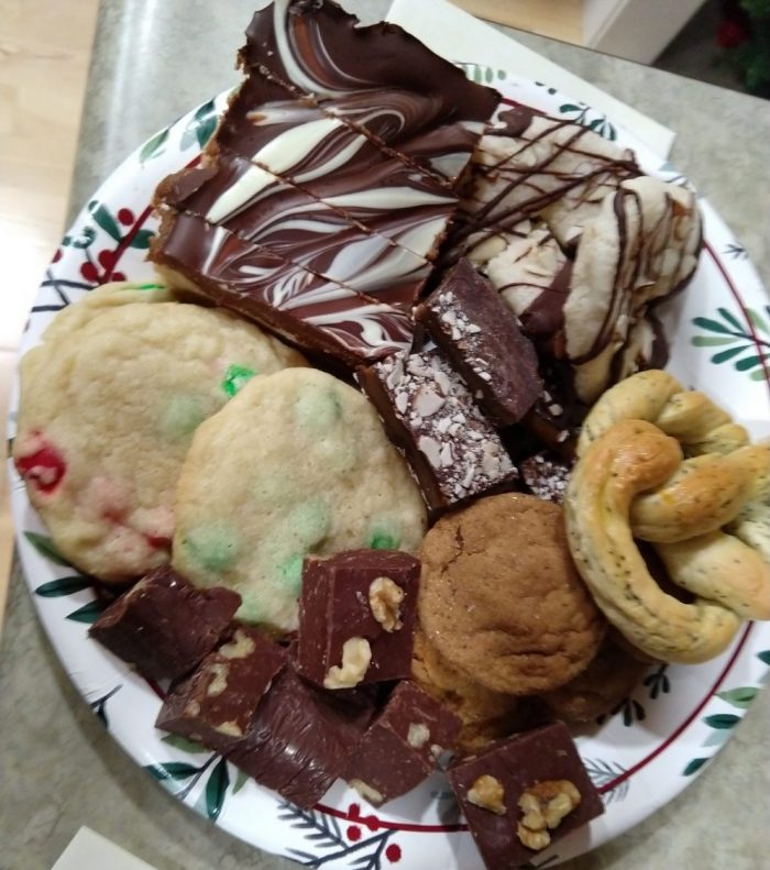 a large plate of holiday cookies including: ginger snaps, fudge, m&m cookies, toffee, millionarie's shortbread, almond horns, and a poppy seed pretzel