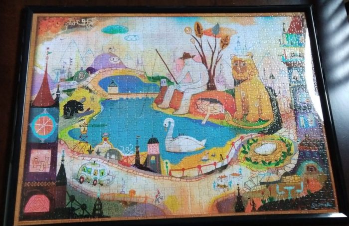 a 20 by 28 inch puzzle, glued together and set in a black frame. The puzzle features a pond with a giant swan, a lion with a suspicious look on his face, and lots of other whimsy
