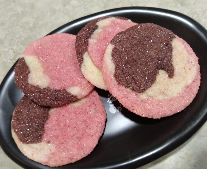 a small plate of cookies. The cookies are marbled, consisting of chocolate, strawberry, and vanilla doughs rolled together. Each cookie is unique.
