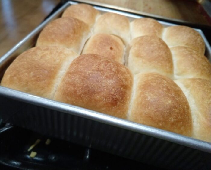 a square pan of fresh-baked rolls that are all baked together like miniature loaves