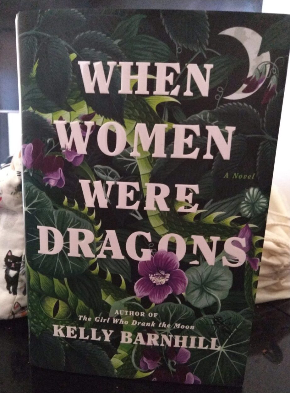 hardback book: When Women Were Dragons. Cover is a riot of dark-green leaves and purple flowers with dragons snaking through them