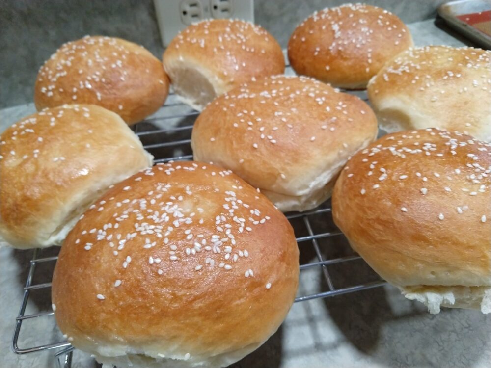 a batch of perfect sesame buns cooling on a wire rack