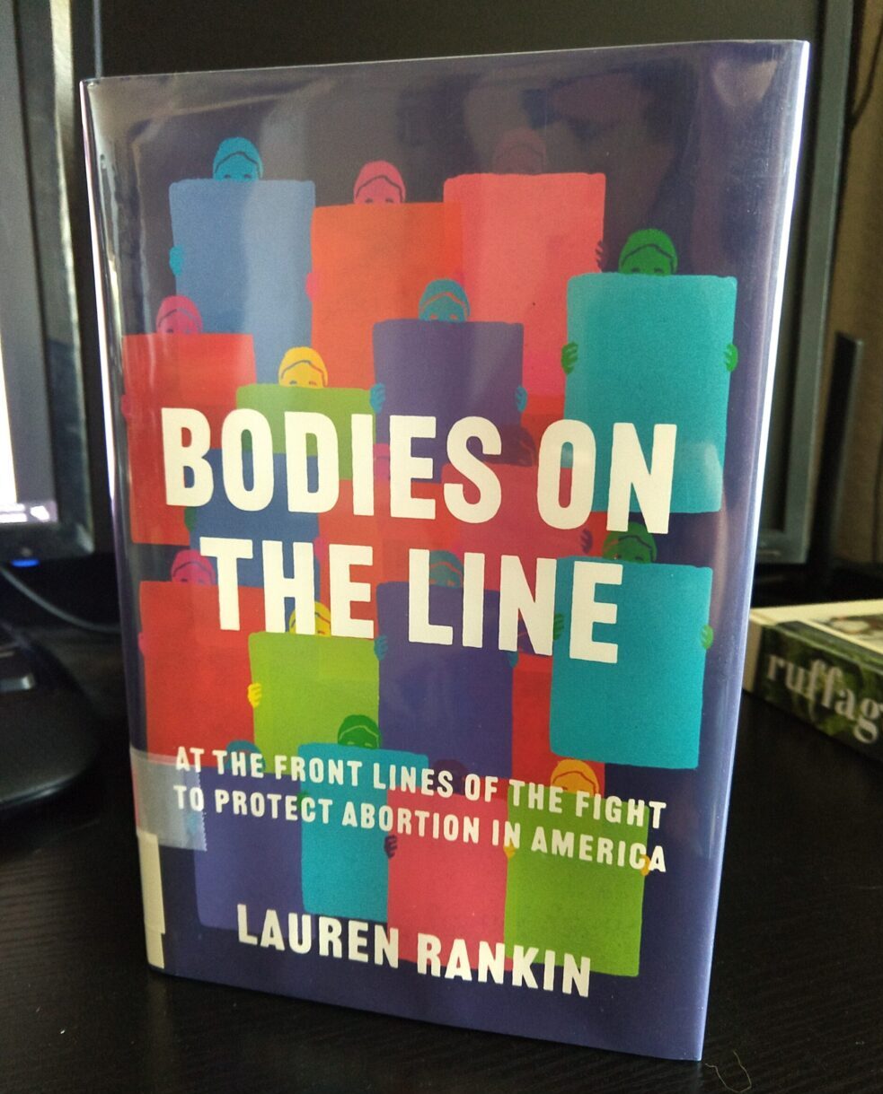 hardcover library book: Bodies on the Line by Lauren Rankin. The cover shows stylized drawings of people hiding behind boards or shields.