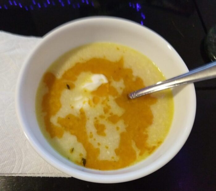 a bowl of corn soup, red-orange oil diffusing across the surface