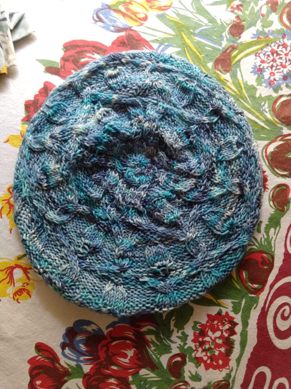 multi-colored blue, knitted beret with a cable pattern repeating in a circle