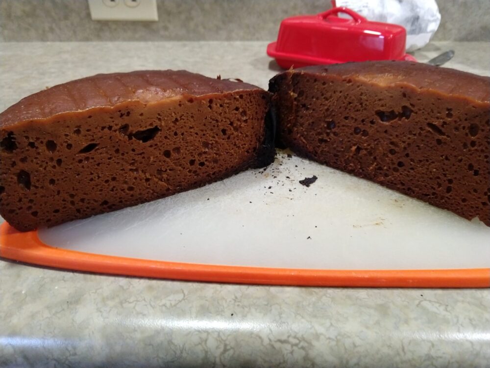 a cross-section of a dense, dark-brown bread that is seriously burned on hte sides and bottom