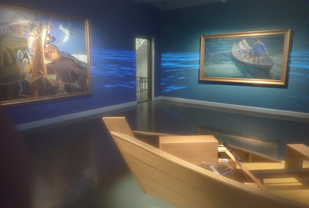 A room in a museum in which the paintings depict men working on boats. A projector covers the walls in rippling water. There is a little boat with a rowing machine that visitors can sit in to row along with the paintings