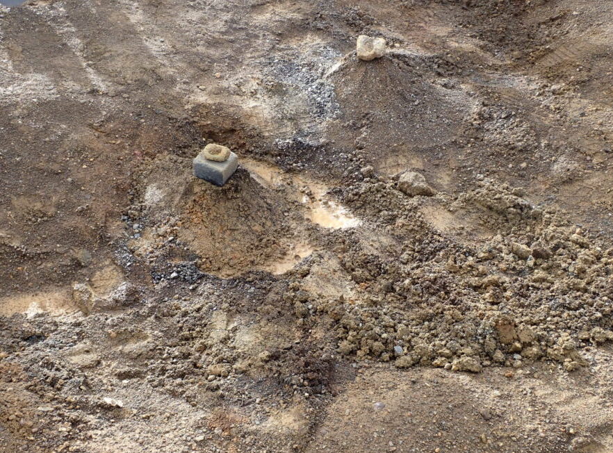 A picture of the ground showing two small piles of dirt, each topped with a rock.