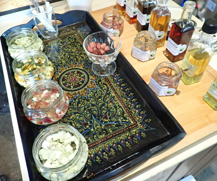 a tray with several small jars of feta goat cheese and tiny rounds of goat sausage. There is also a variety of spreads and oils