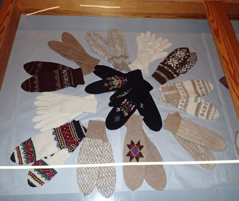 a glass case dispalying about 12 pairs of Icelandic mittens knitted using traditional motifs