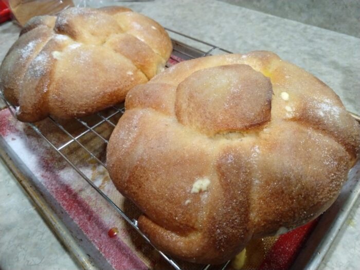 two round loaves of pan de muerto on a wire rack