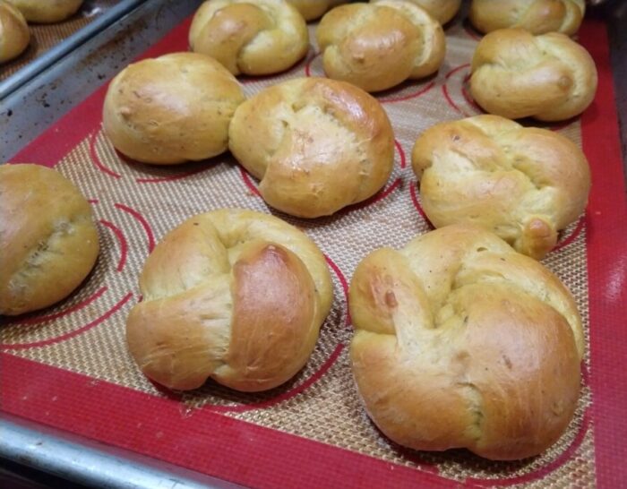 golden, knotted rolls on a baking sheet