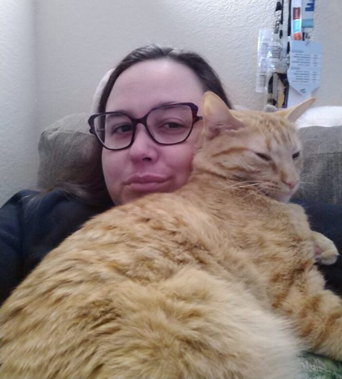 Me and Fritz the cat snuggling. He is leaned up on my shoulder and against my face.