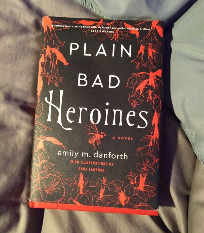 hardcover book: Plain Bad Heroines. Black cover with red illustrations of flowers and yellowjackets