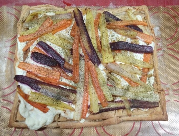 a puff pastry layered with a cheesy blend and thinly sliced rainbow carrots