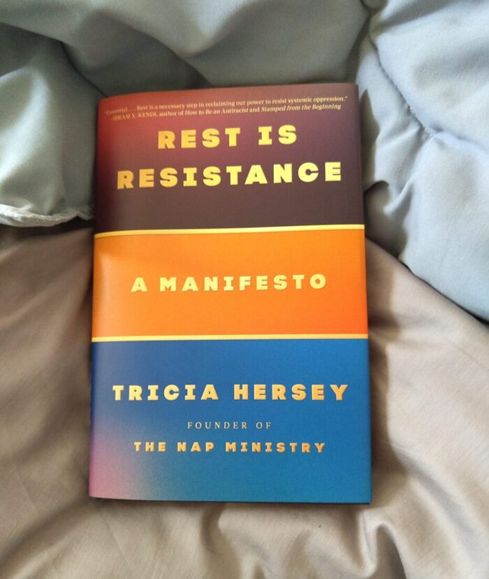 hardcover book: Rest is Resistance. The book is on top of a pile of bedding