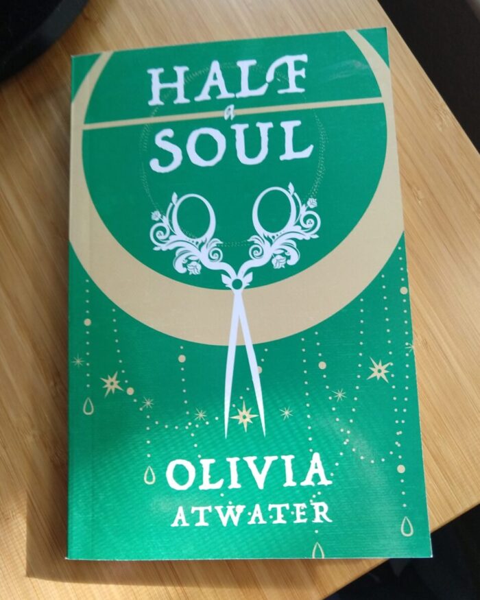 paperback book: Half A Soul. Green cover with an illustration of fancy embroidery scissors