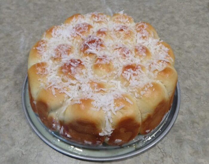 rolls cooked in together in a round pan, topped with shredded coconut and a drizzle of sweetened condensed milk