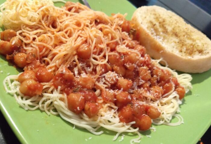 a plate of noodles covered in a chickpea and tomato sauce