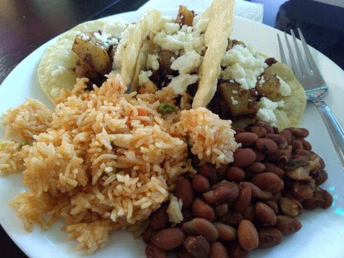 a plat with a big pile of rice, beans, and three tacos