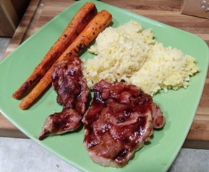 a plate of chicken with hibiscus barbecue sauce, risotto, and carrots