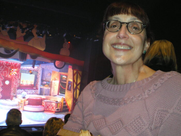 my mom, smiling at the camera, the set of Pee Wee's Playhouse on the stage in the background