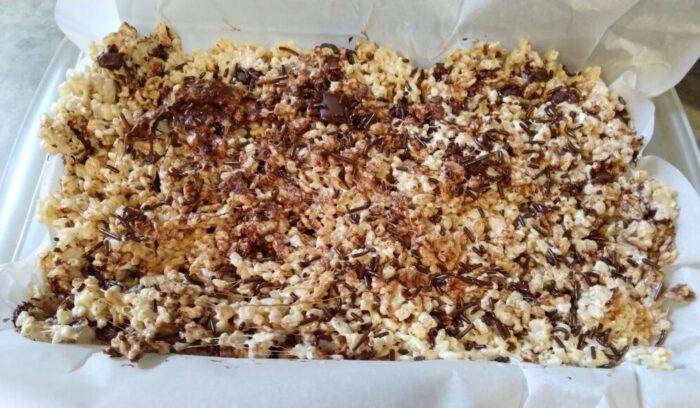 a pan of rice krispie treats that have chocolate chunks in them and chocolate sprinkles on top