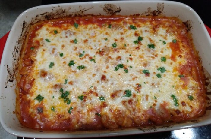 a casserole dish filled with beans and tomato sauce, topped with melty cheese
