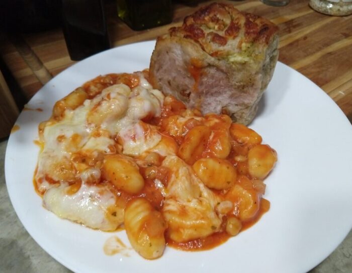 a plate of gnocchis and chickpeas covered in tomato sauce and topped with melty cheese