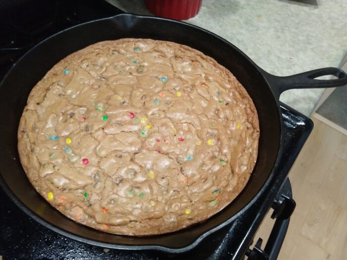 One giant cookie filling a cast iron skillet. There are mini M&Ms baked in.