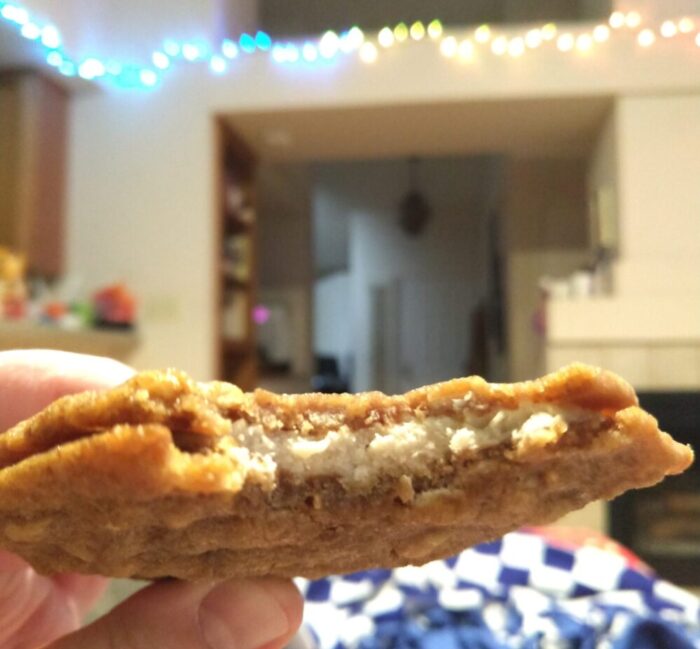 oatmeal sandwich cookie with a bite taken out of it, tilted to show the frosting filling