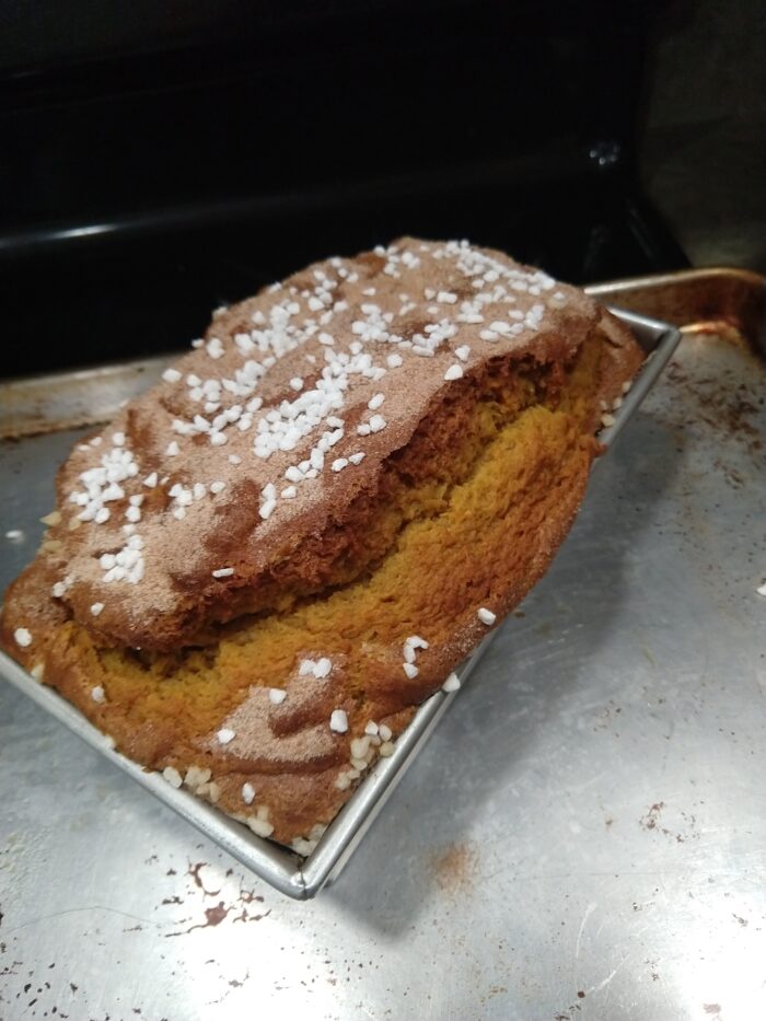 A tall loaf of pumpkin bread topped with cinnamon sugar and pearl sugar