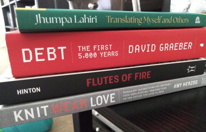 a stack of books including: Translating Myself and Others, Debt the First 5,000 Years, Flutes of Fire, and Knit Wear Love