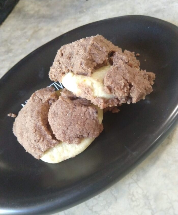 a pair of cookies on a small plate. The cookies are covered with a very crumbly chocolate craquelin