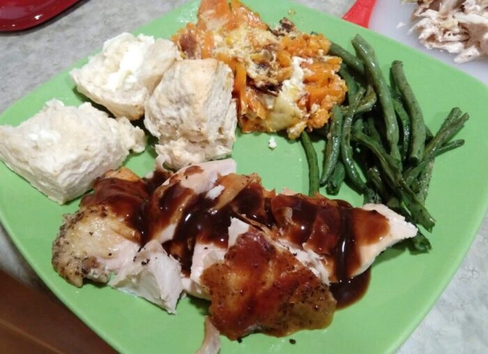 a plate of roast chicken, green beans, sweet potato gratin, and biscuits