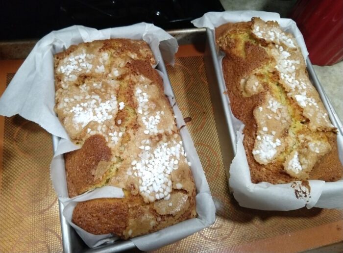 two orange loaf cakes topped with sugar. A nice crust has formed on the top and there's a big crack along the top of the loaf