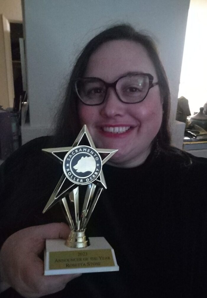 Me smiling and holding up my award for 2023 Announcer of the Year