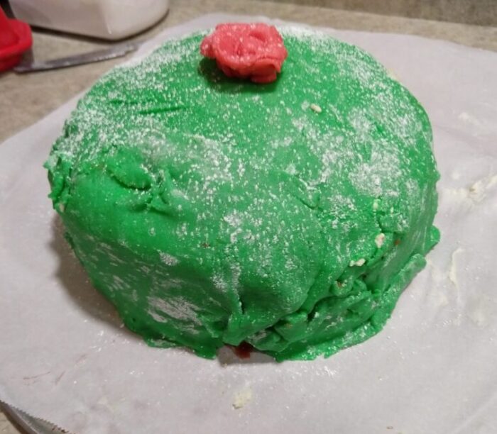 a big, round cake covered in green marzipan and sprinkled with powdered sugar