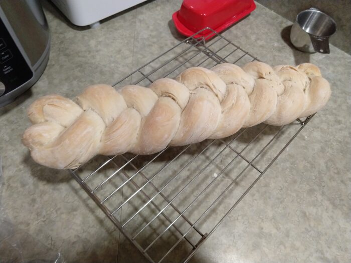 a braided loaf of bread cooling on a rack