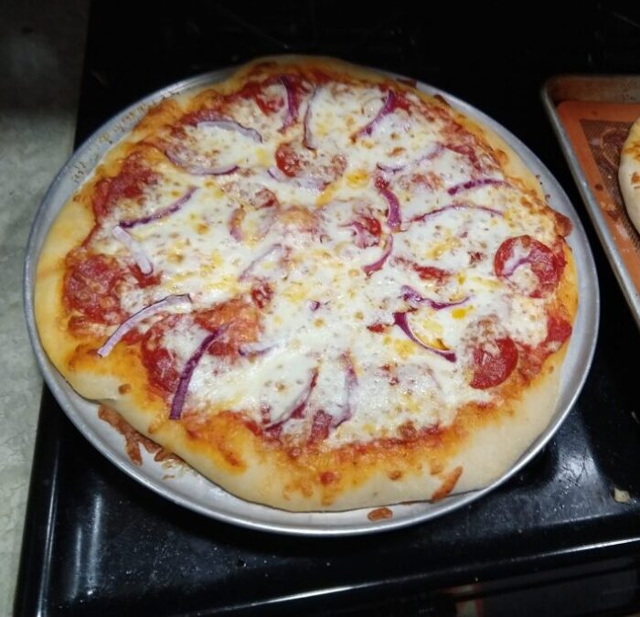 A homemade pizza topped with pepperoni and red onion