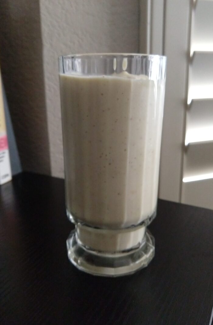 a glass containing a light-yellow colored smoothie