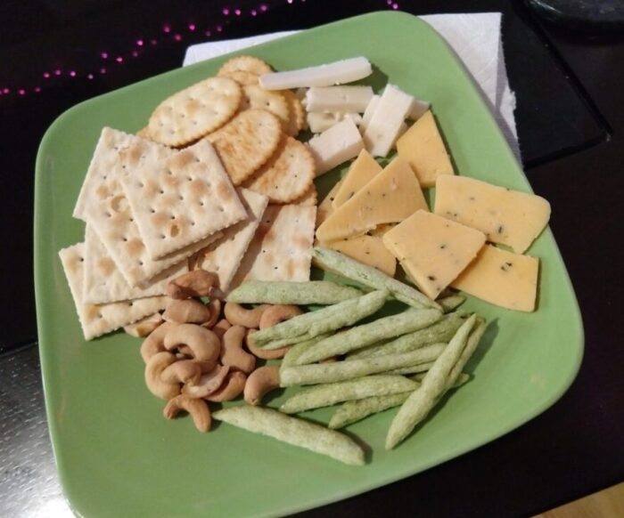 a plate of cheese and crackers, cashews, and pea crisps