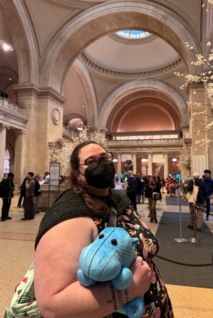 me in the Met's lobby, holding a blue hippo stuffed animal that I just bought